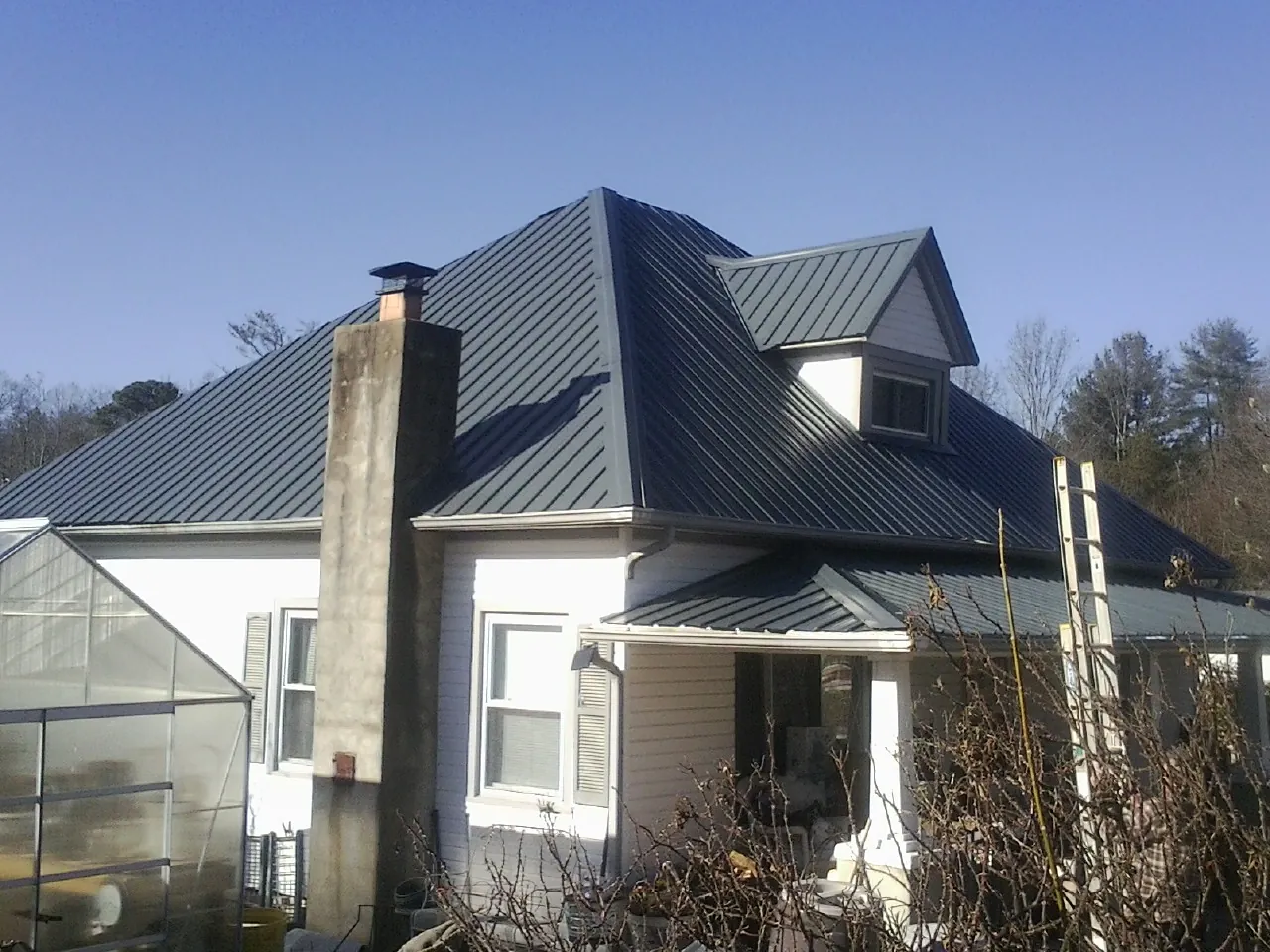 Dark blue standing seam metal roof on a white farmhouse with dormer — Slate & Tile Roof Repair by Roofing Brothers in Rockland