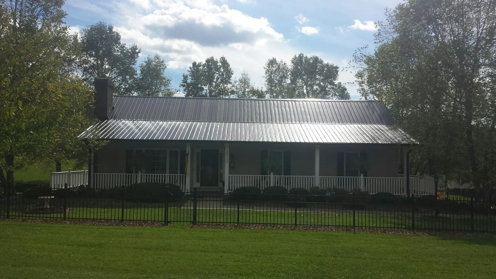Gray metal roof on a brick ranch with a full width front porch — Gutter Guard Installation work by our crew in Rockland